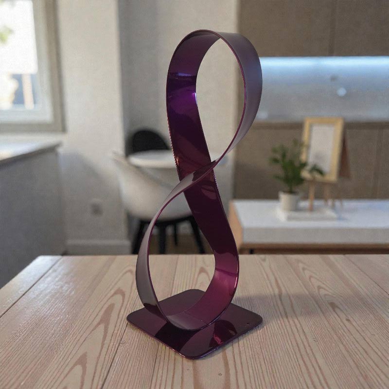 Sculpture métal ruban Möbius violet façonnée à la main pièce artisanale moderne en situation